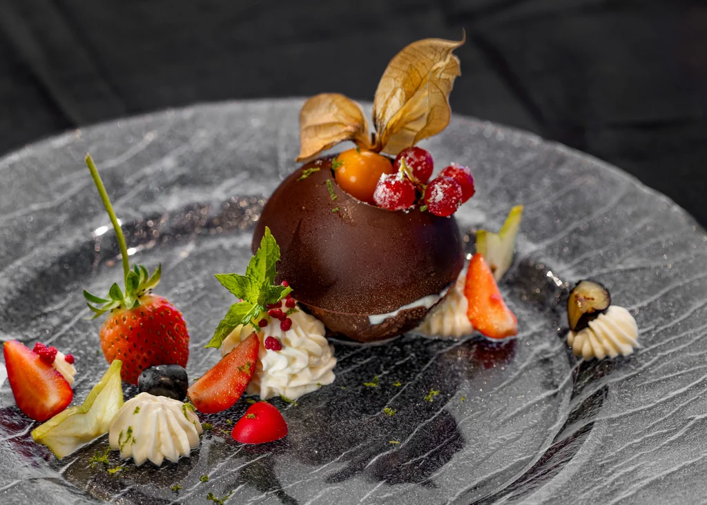 Die Adresse für Wellness in Bayern: Ihr Hotel in St. Englmar Schokoladendessert mit Beeren und Sahne auf schwarzem Teller dekoriert