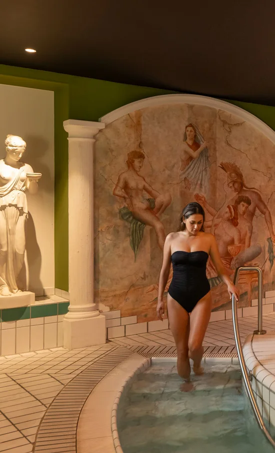 Die Adresse für Wellness in Bayern: Ihr Hotel in St. Englmar Frau steigt in beheiztes Spa-Becken in einem römisch inspirierten Wellnessbereich