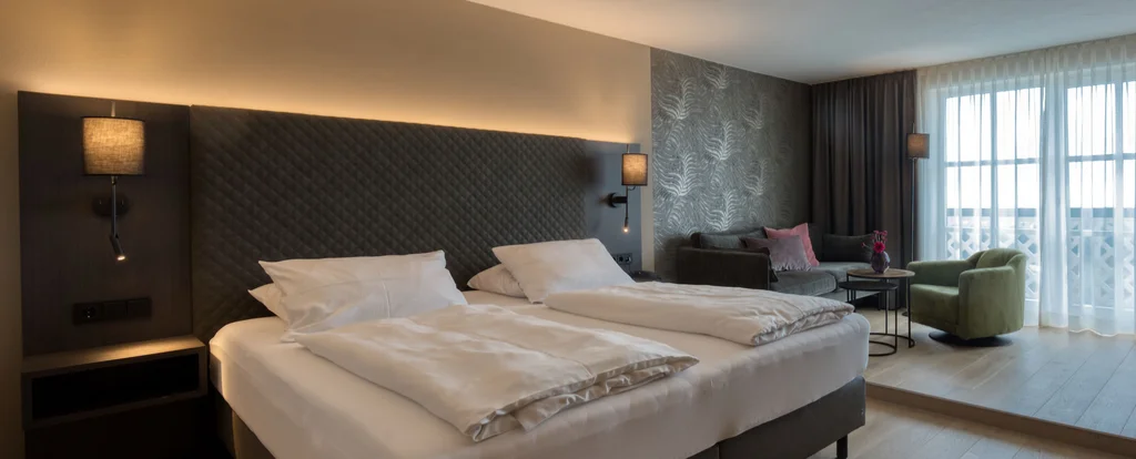 Die Adresse für Wellness in Bayern: Ihr Hotel in St. Englmar Modernes Hotelzimmer mit Doppelbett und Sitzbereich am Fenster
