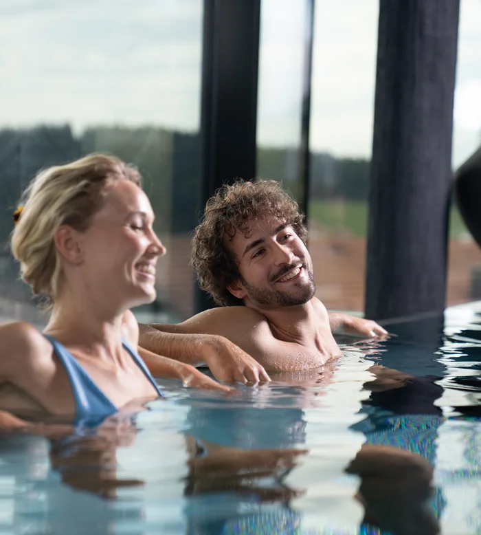 Die Adresse für Wellness in Bayern: Ihr Hotel in St. Englmar Ein lächelndes Paar entspannt gemeinsam in einem Innenpool